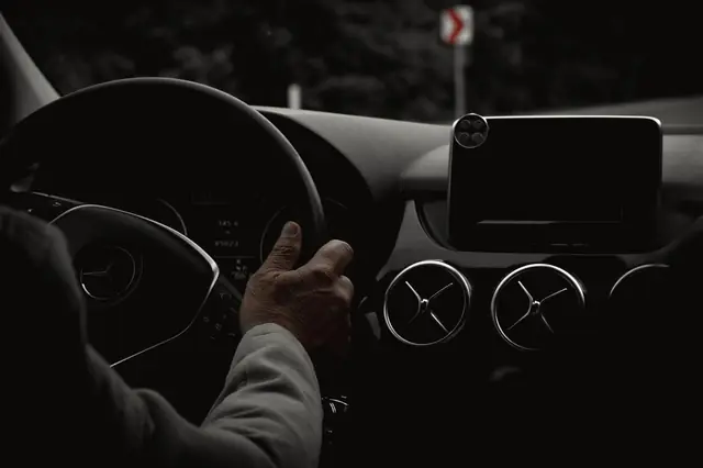 Mains d'un chauffeur sur le volant d'une berline, de nuit